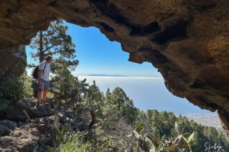 Wanderer vor der Höhle Cueva de Unchico mit Blick auf Gran Canaria