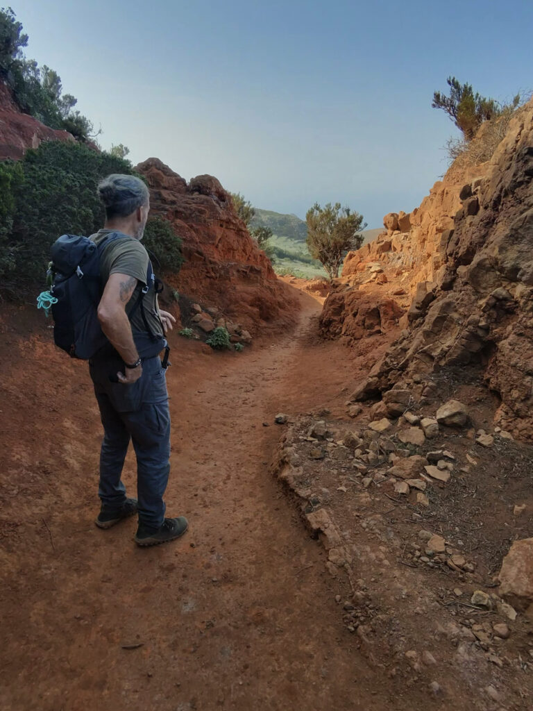 Hiker on the hiking trail via Teno Alto on red soil